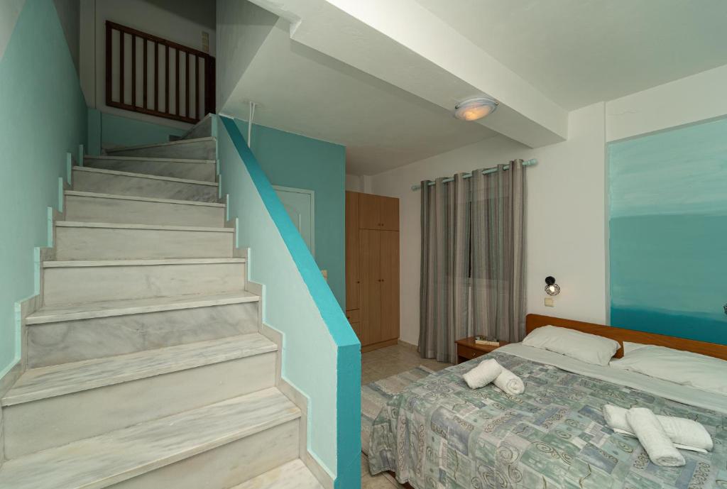 Εσωτερικό μεζονέτας στο Blue Houses με διπλό κρεβάτι και μαρμάρινη σκάλα που οδηγεί στον επάνω όροφο.